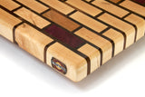 close up of medium maple brick pattern end grain cutting board with cherry and purple heart accents. 